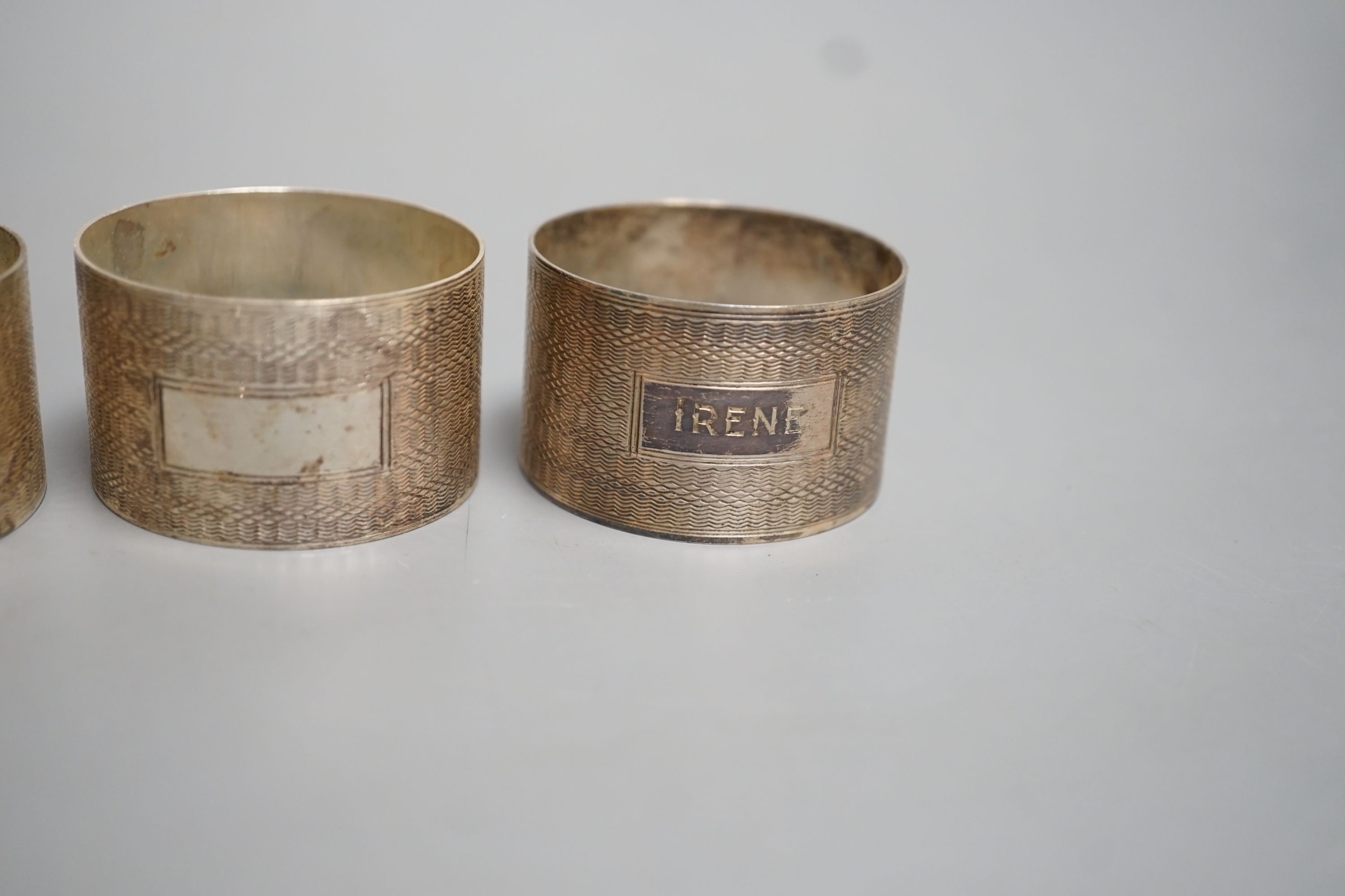 A set of four George VI engine turned silver napkin rings, H. Bros, Birmingham, 1943/4, two engraved with names.